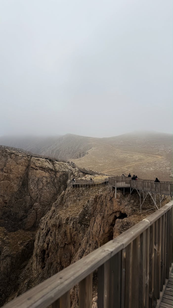 ours-journey A foggy mountain landscape with an observation deck and distant hikers.