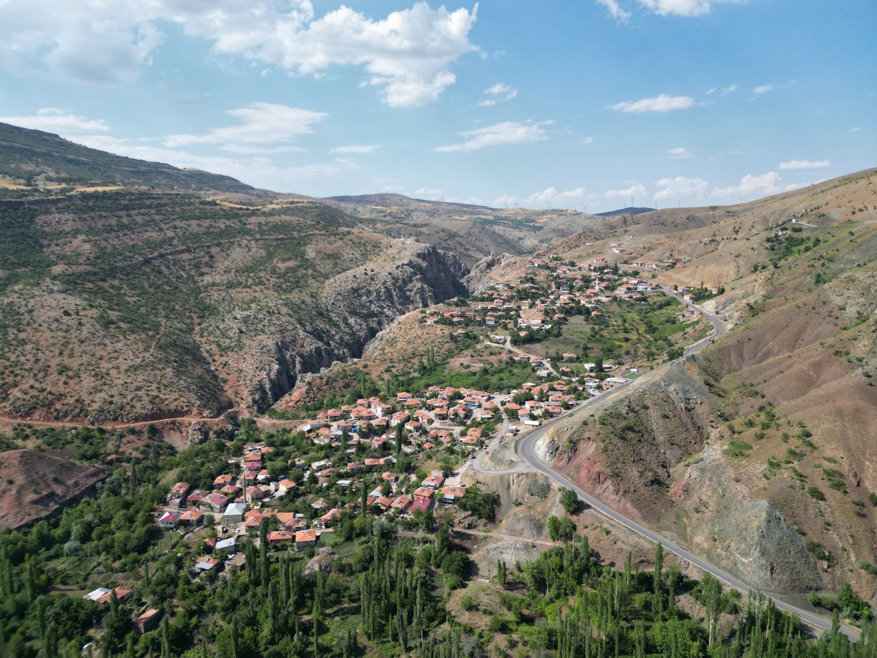 services-01 A captivating aerial shot of a rural town nestled in a hilly landscape under a clear blue sky.